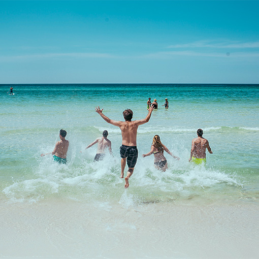 Foto: Strand und Menschen die ins Wasser rennen