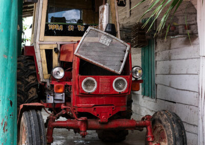 Foto: alter Traktor, rot lackiert, in einem Unterstand aus Holz