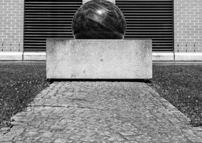 Foto: Skulptur mit schwimmend gelagerter Kugel vor symmetrischer Fassade