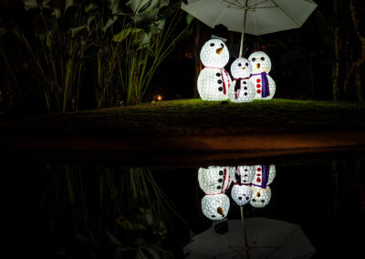 Foto: künstliche Schneeleute unter einem Sonnenschirm auf einer Insel in einem Teich
